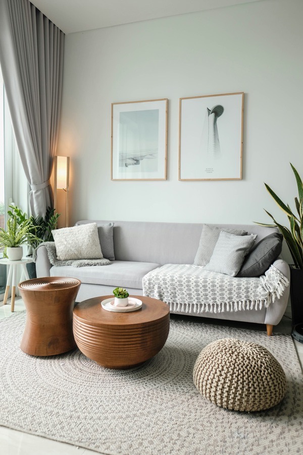 Living room with a knitted floor pouf on the rug and two framed prints above the sofa