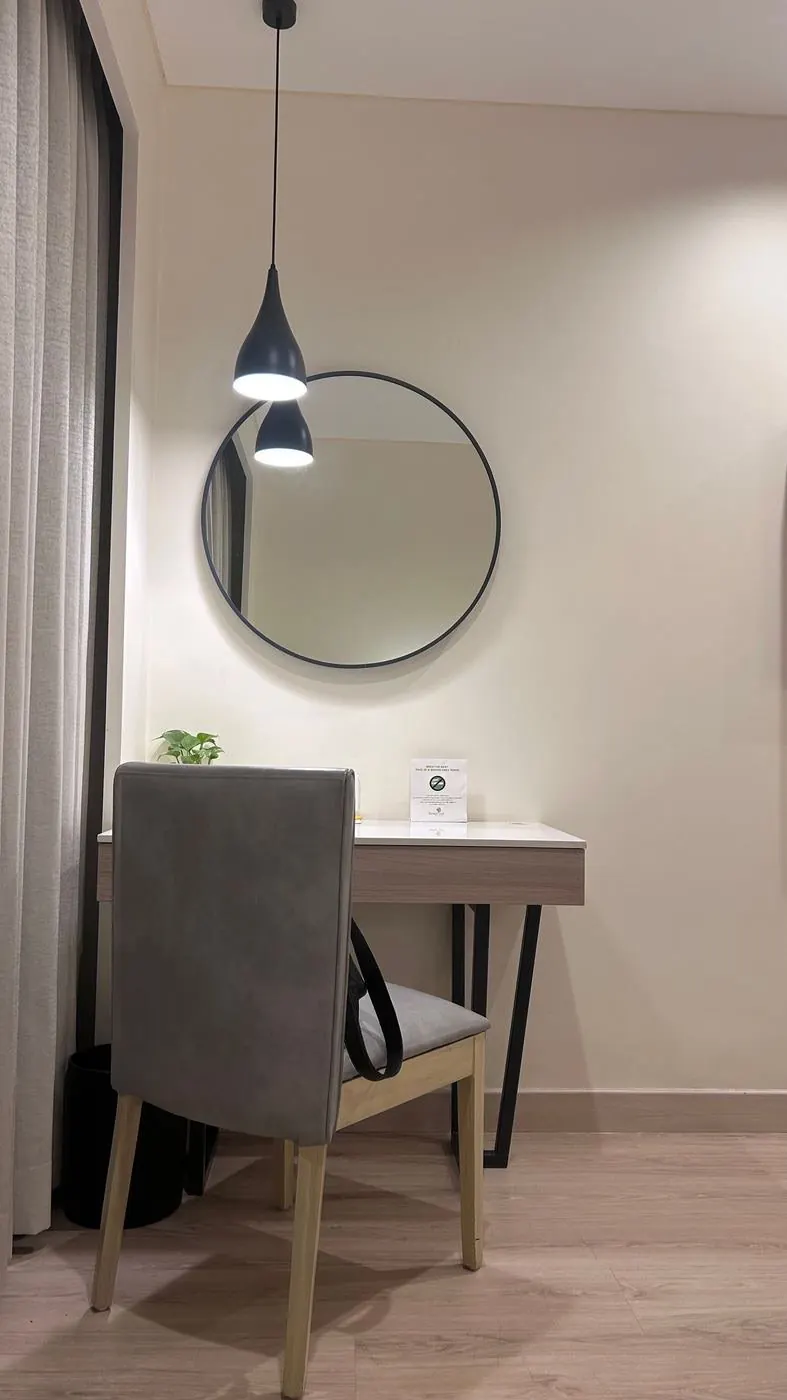 Rincón de despacho con una pared crema, un espejo redondo, un escritorio y una silla gris, antes de cualquier edición con IA
